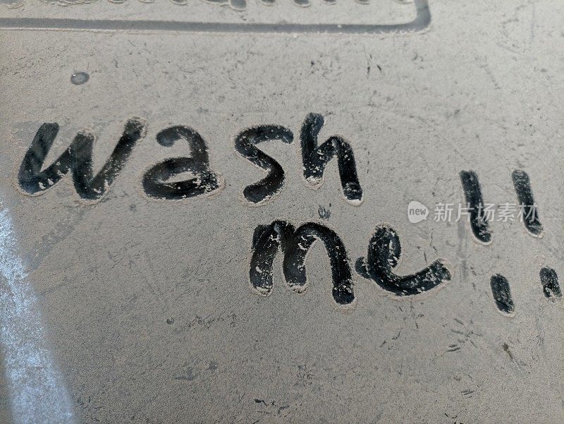 脏的车窗。满是灰尘的脏车窗上写着“洗我”。脏的车窗"现在就给我洗"这句话
